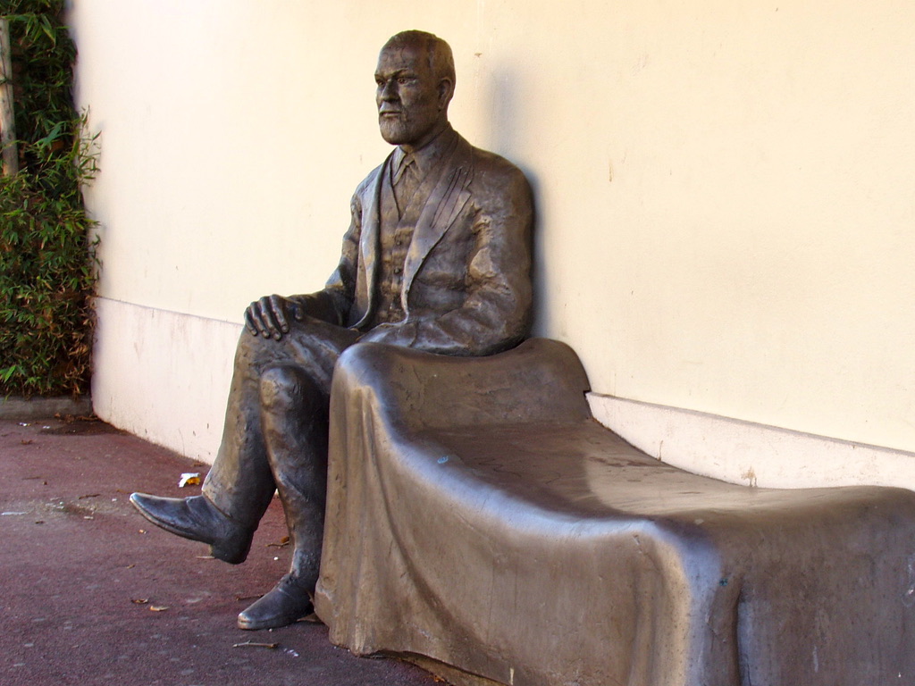 Sigmund Freud accoudé à la tête d'un divan en attente d'un patient